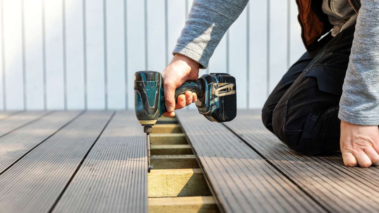 Skilled professional using a drill to secure deck planks, ensuring a stable and long-lasting foundation. This image showcases the precision and care involved in Best Deck Installation and Maintenance services.