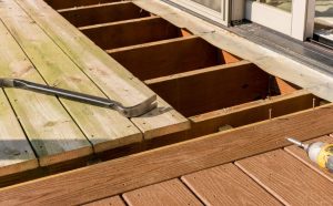 A close-up view of a partially built deck showing exposed wooden joists, a pry bar, and decking tools illustrating professional Deck Building Services in progress.