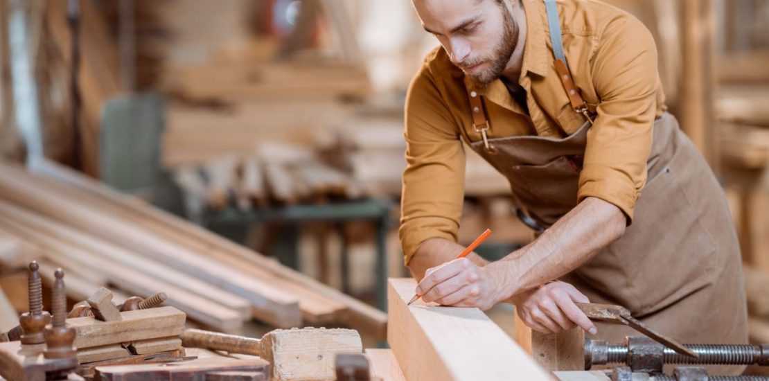 Expert carpentry services performed by a skilled carpenter, measuring and marking wood in a professional workshop.