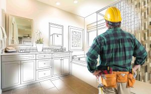 A skilled contractor in a green plaid shirt and yellow hard hat envisions a bathroom transformation with the Best Remodeling Services. The image creatively blends a partially drawn bathroom design with a real, stylish tiled wall, illustrating the journey from concept to reality.