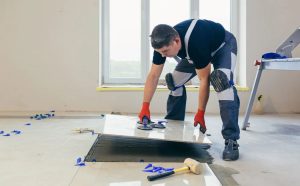 Skilled worker installing large ceramic tiles with precision tools, demonstrating the quality and expertise of the best flooring services.