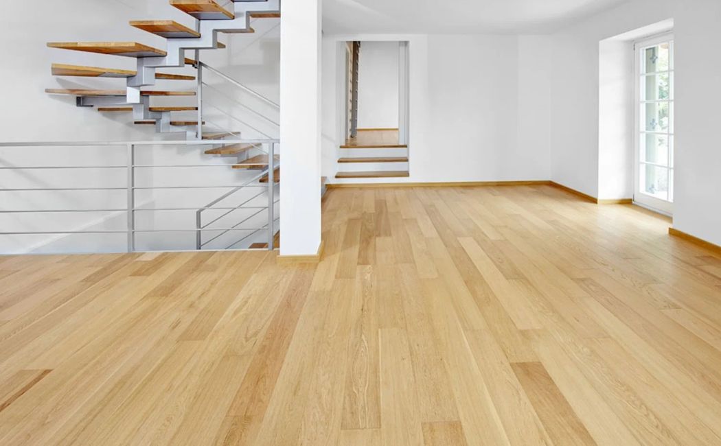 Modern living space with sleek wooden flooring and minimalist staircase, showcasing professional flooring services for residential interiors.