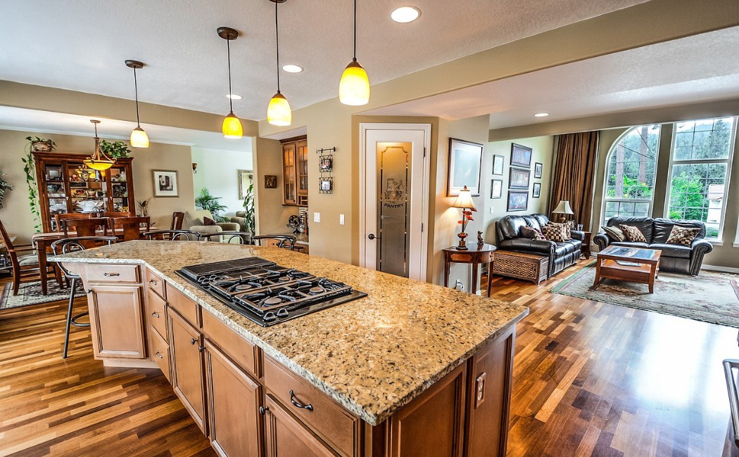 Beautifully remodeled open-concept kitchen and living area with granite countertops, hardwood floors, and modern lighting by professional remodeling services.