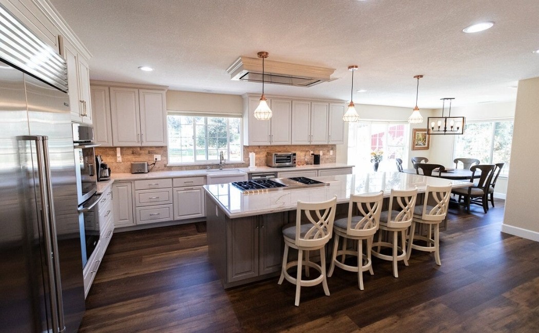 Modern open-concept kitchen with white cabinets, large island, and pendant lighting, showcasing expert kitchen remodeling services for a stylish and functional space.