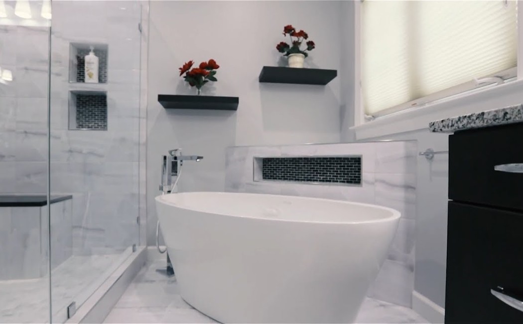 A modern bathroom with a sleek freestanding tub, glass shower, and stylish shelving, showcasing the quality results of professional Bathroom Remodelling Services.
