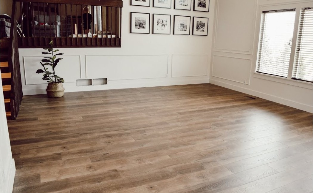 The image showcases a spacious room with light laminate flooring, featuring minimalist decor and natural light. Perfect for a fresh, modern home with laminate flooring services.