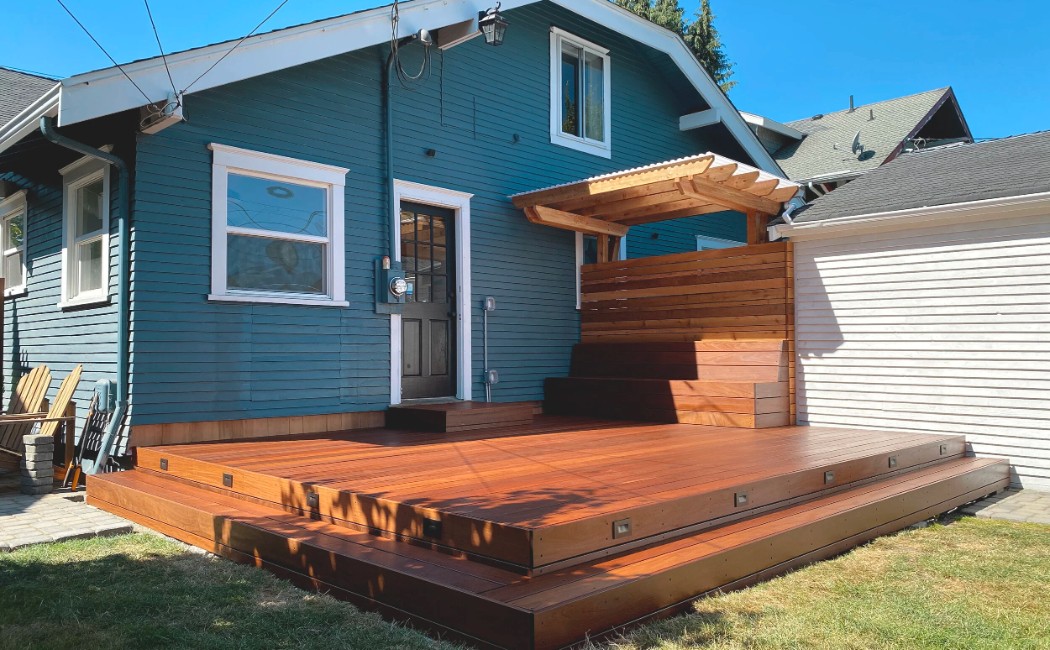 Custom wood deck highlighting Deck Building Services, featuring a multi-level platform, integrated steps, and a privacy screen attached to a residential home.