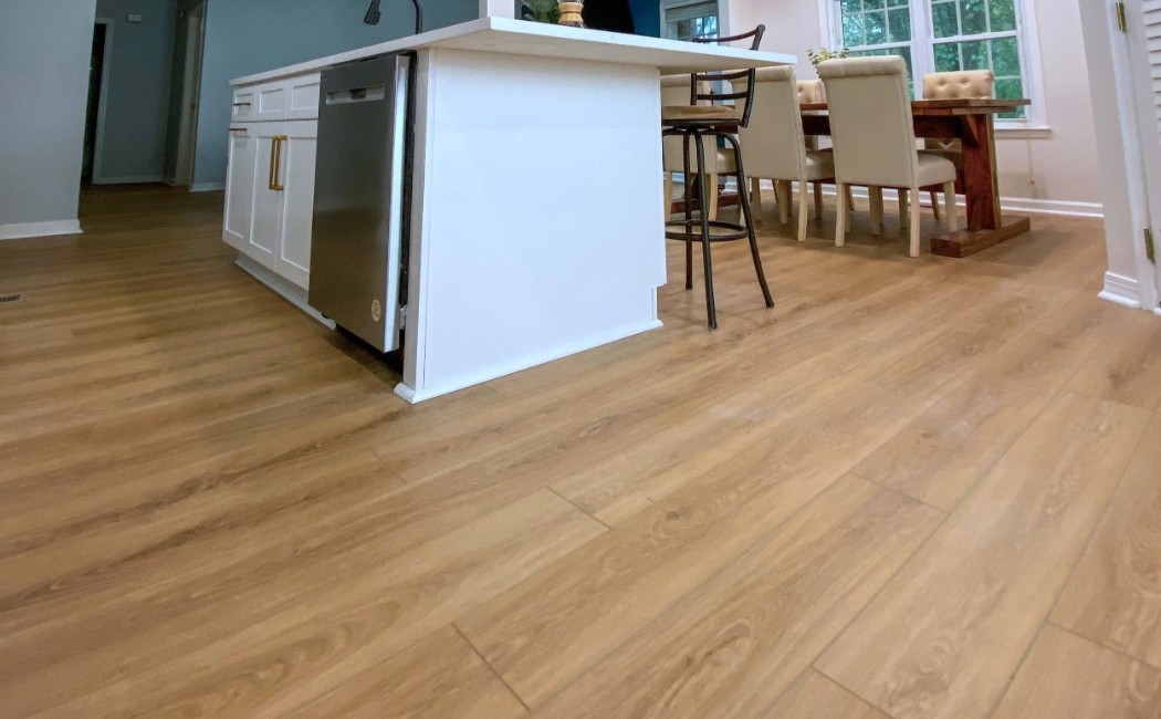 Open Kitchen & Dining Area with Premium LVP Flooring Services Open kitchen and dining area showcasing premium LVP flooring services with warm wood-look vinyl planks that add durability, style, and seamless flow to the space.