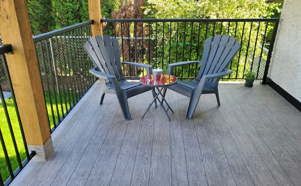 Modern outdoor deck showcasing Deck Building Services, featuring composite flooring, black metal railings, and a cozy seating area overlooking a landscaped backyard.