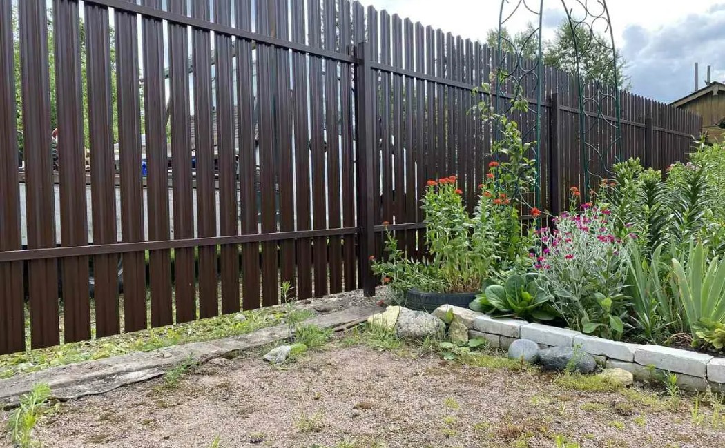 Durable Fence Repairing Services for a Secure and Stylish Garden A well-maintained metal fence alongside a landscaped garden, highlighting durable and professional Fence Repairing Services for enhanced property security and appearance.