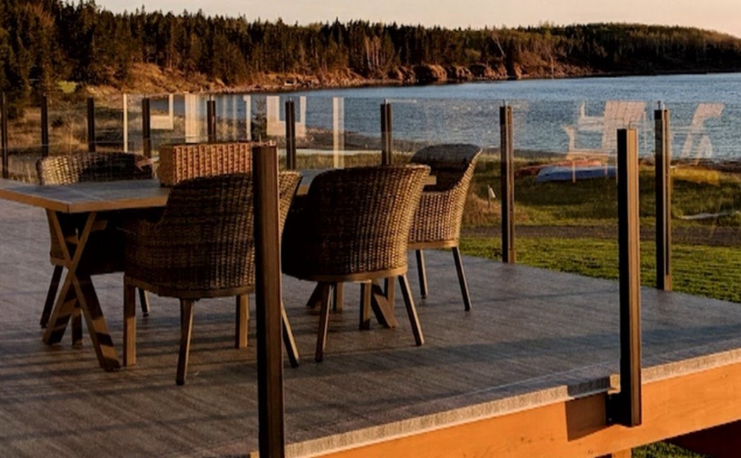 Weatherproof deck overlooking a scenic waterfront, featuring durable flooring, modern railing, and outdoor dining furniture.