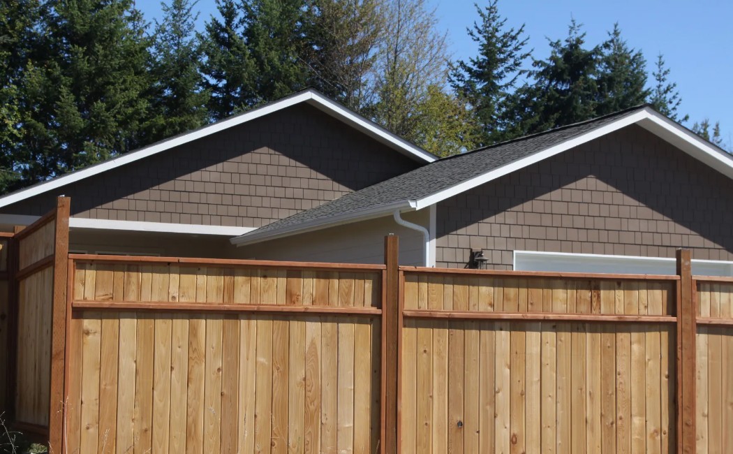 Wooden Privacy Fence Installation for Secure and Stylish Property Boundaries Wooden privacy fence installed around a residential property with modern homes and trees in the background, showcasing professional Fence Installation Services for secure and attractive boundaries.