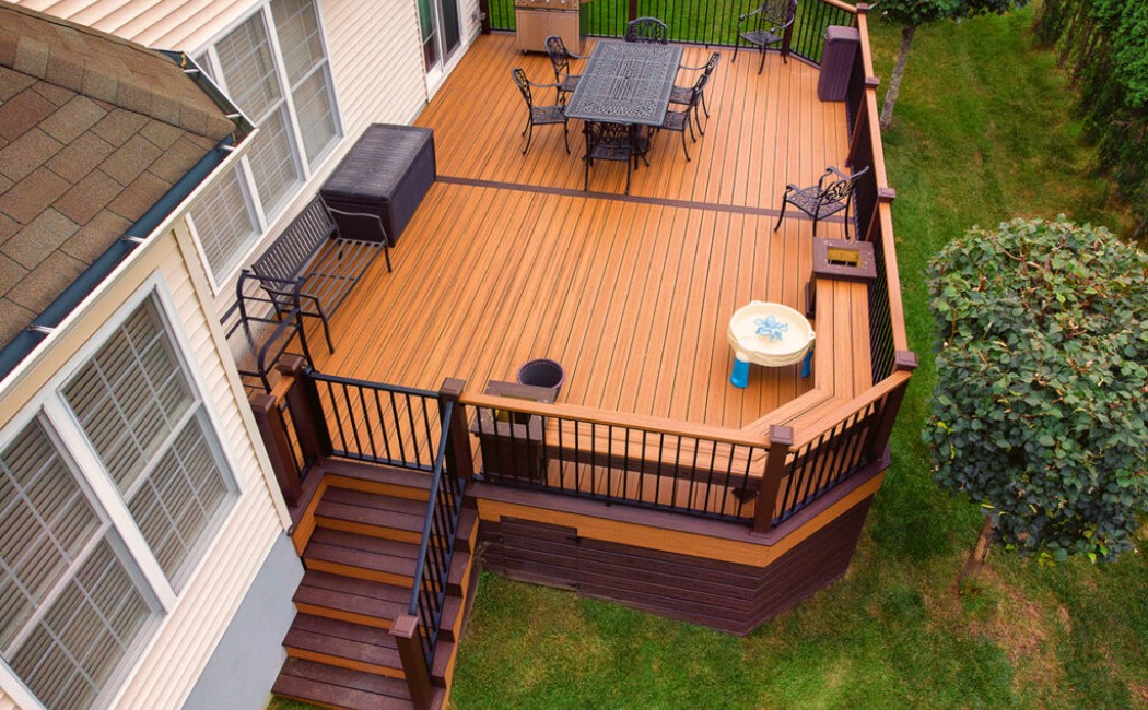 Spacious backyard deck showcasing Custom Deck Building Services, featuring composite decking, built-in seating, railings, stairs, and an outdoor dining and grill area connected to the home.