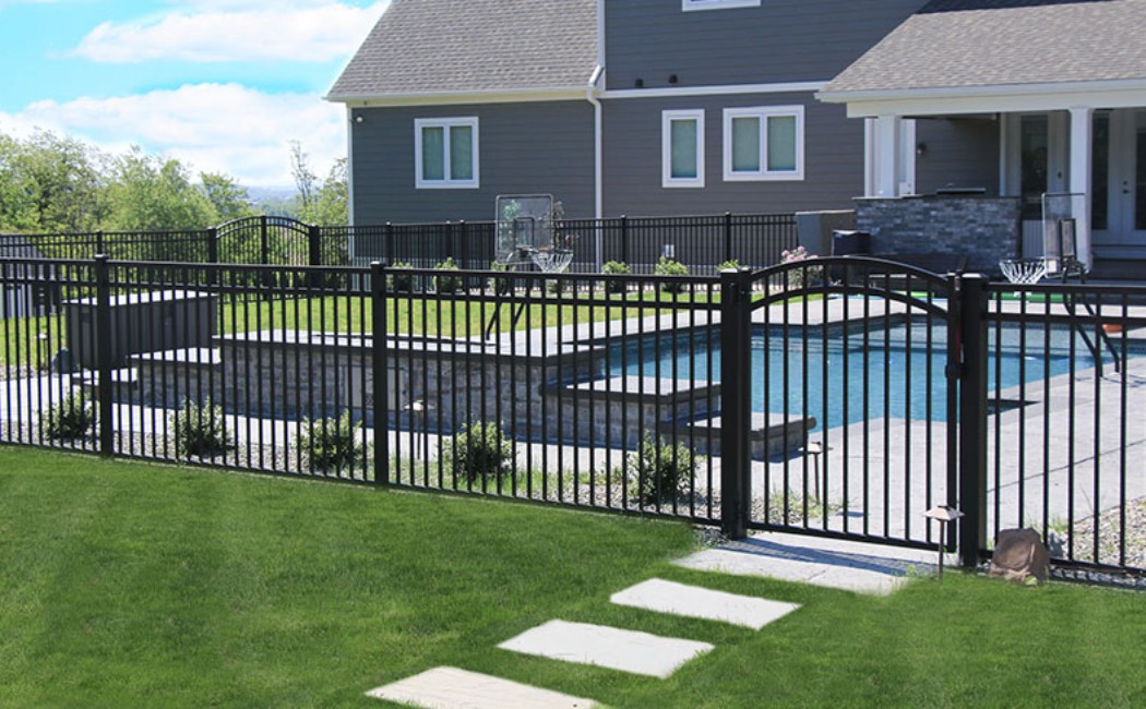 Professional Fence Maintenance Services for Pool Safety Black metal pool fence surrounding a residential backyard, showcasing professional Fence Maintenance Services to ensure safety, durability, and long-lasting protection.