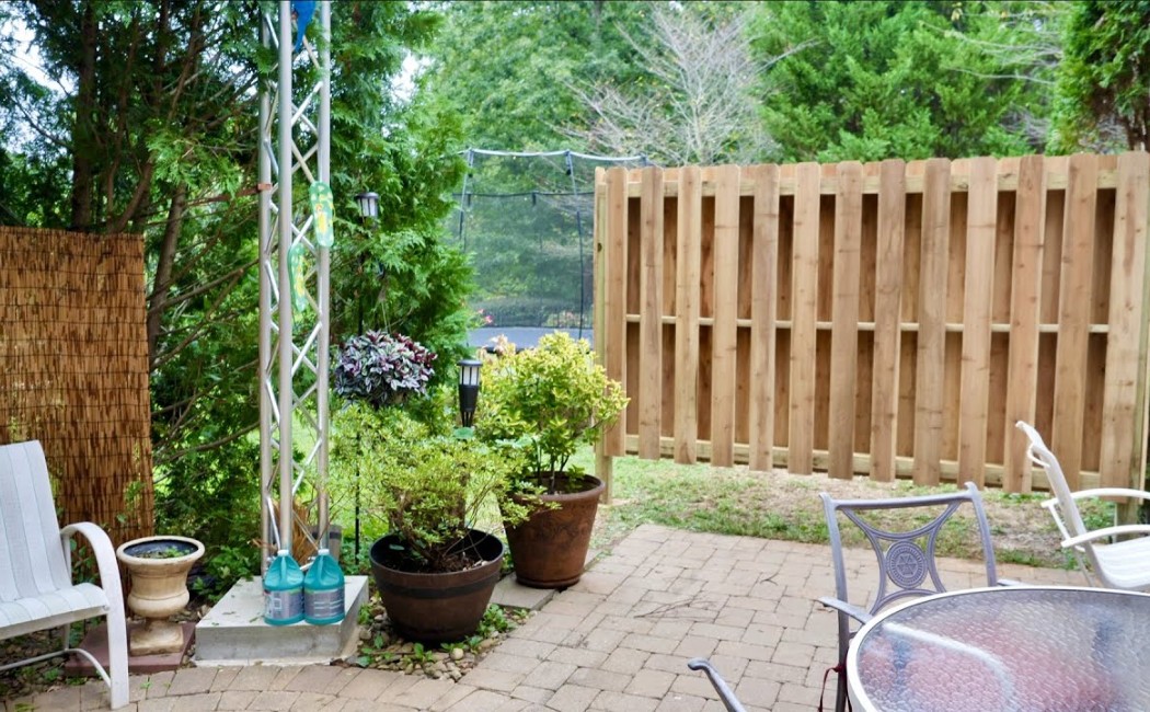Backyard patio with a newly repaired wooden privacy fence, highlighting professional Fence Maintenance Services to improve durability, security, and outdoor appeal.