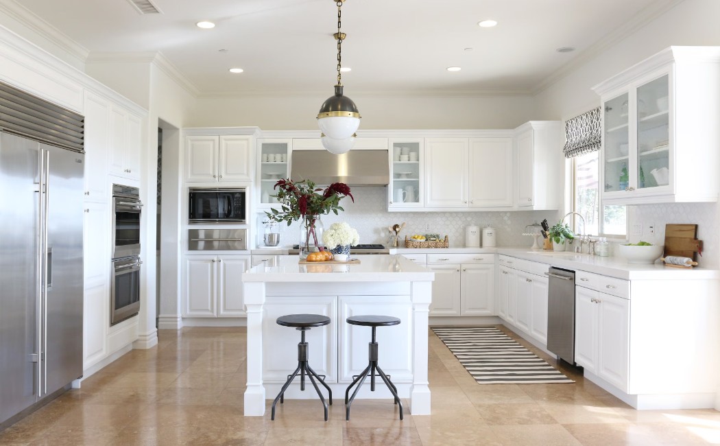 Elegant white kitchen with a spacious island, stainless steel appliances, and modern lighting, showcasing the craftsmanship of a professional Kitchen Remodeling Company.