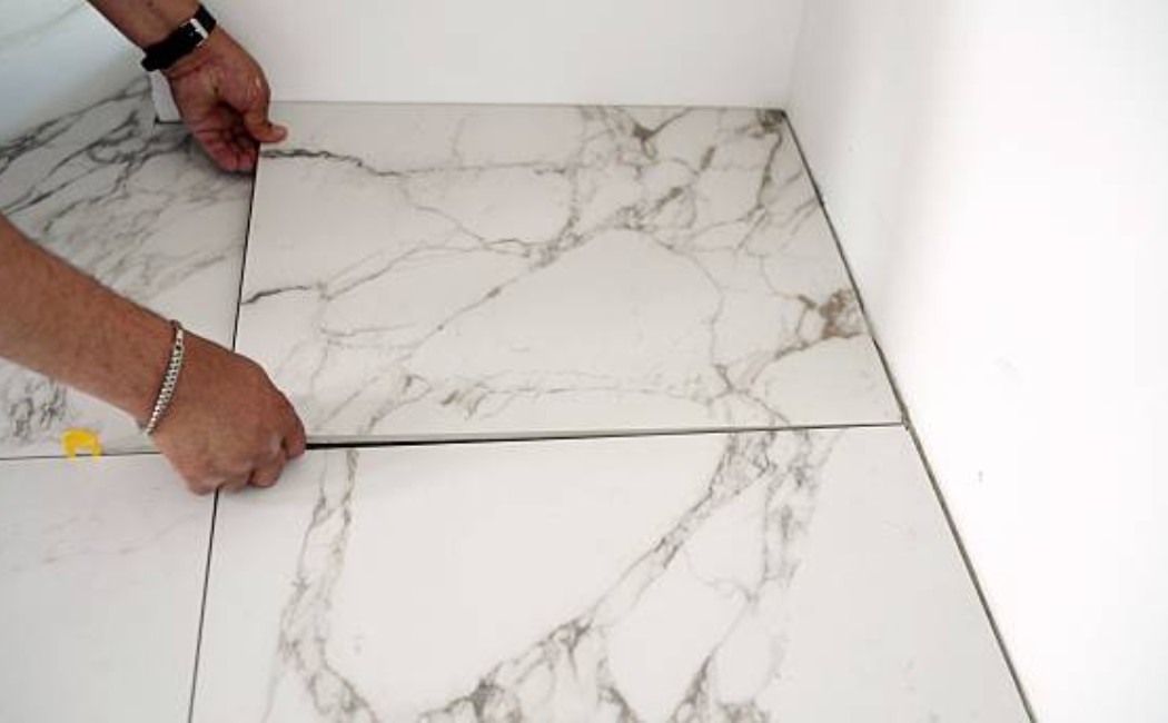 Tile Installation Company expert aligning large marble-look floor tiles carefully to ensure precise spacing and a seamless finish during professional tile installation.