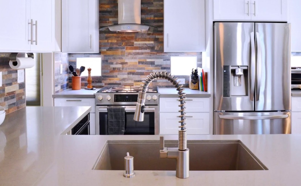 Modern kitchen interior with white cabinets, stainless steel appliances, and a central sink, showcasing professional Kitchen Remodeling Services with a sleek, contemporary design.