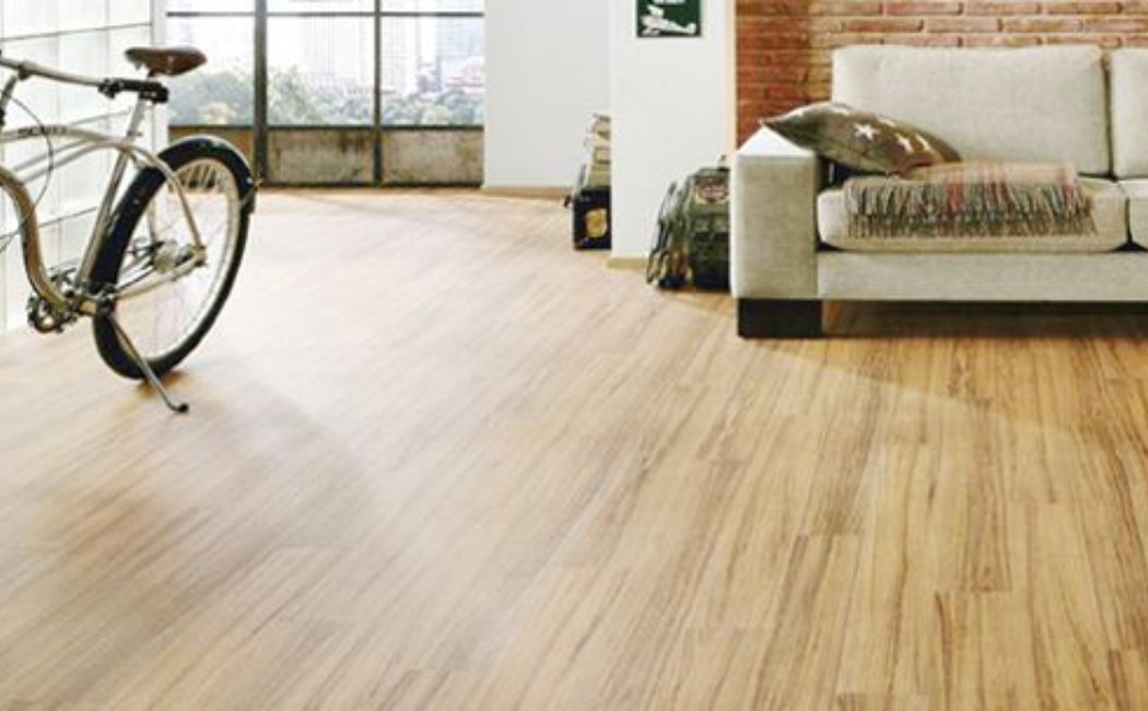 Bright modern living space with light wood-look floors, a bicycle, and cozy sofa, expertly finished by a trusted Laminate Flooring Company.